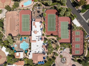 An aerial view of a residential area with multiple tennis courts, a swimming pool, and surrounding greenery. - South Cherokee in Palm Springs (Palm Springs)