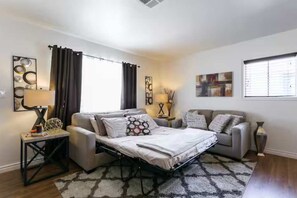 A modern bedroom with a bed, a sofa, a small table, and a lamp. - Central Location One Bedroom Apartment Parking (North Hollywood)