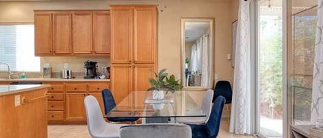 A kitchen with wooden cabinets, a dining table with chairs, a ceiling fan, and a window with a view.