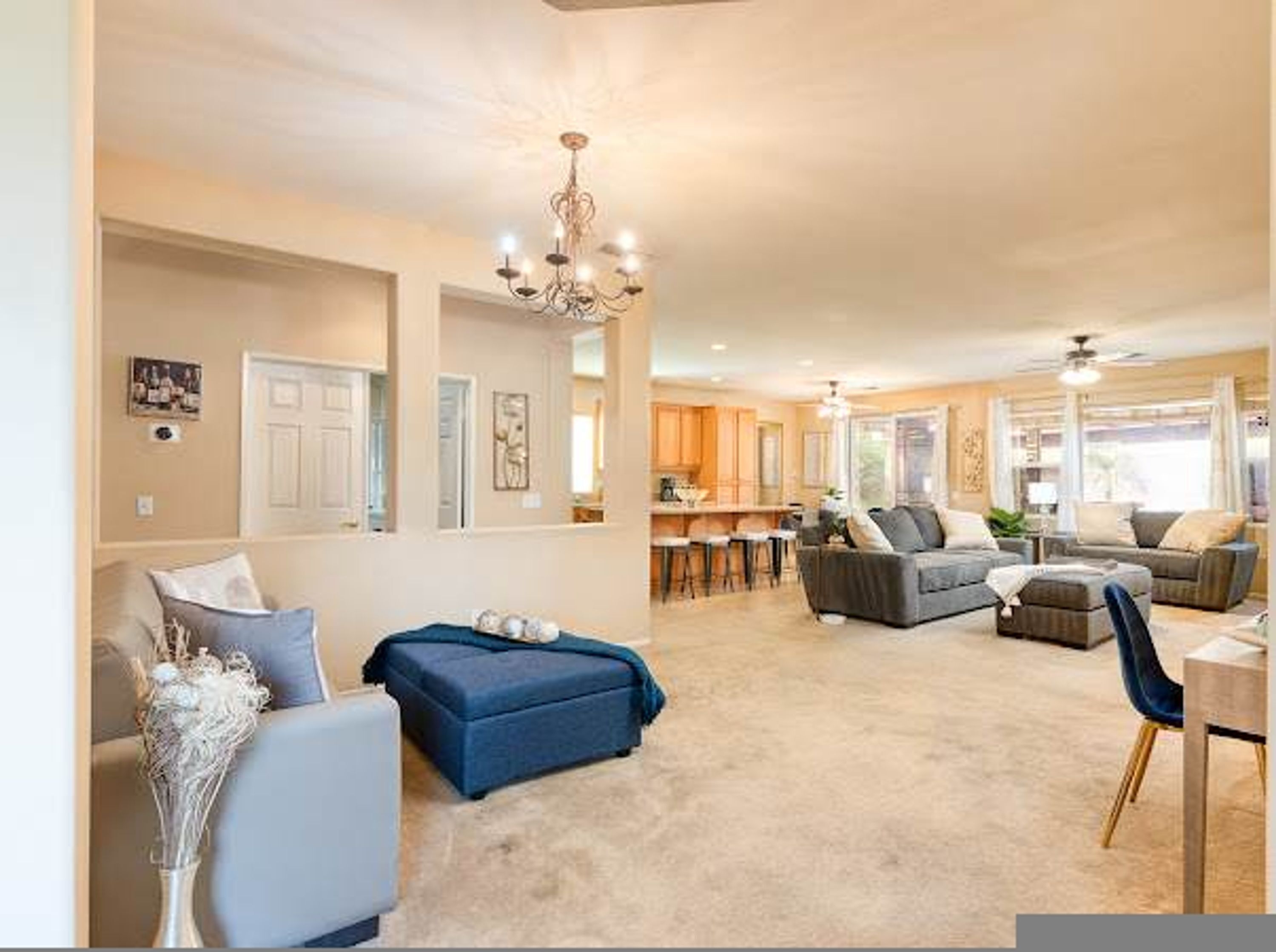 A spacious living area with a sofa, ottoman, and a dining area with chairs.