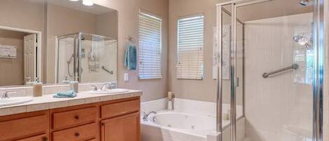 A bathroom with a double vanity, a bathtub, a walk-in shower, and a large mirror.