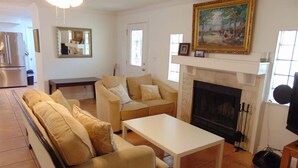 A living room with a sofa set, a fireplace, a painting, and a dining table. - Space for 6 3BR Close to Siesta Beach Downtown (Sarasota)