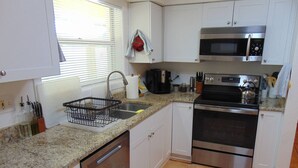 A kitchen with a dishwasher, stove, microwave, and granite countertop. - Space for 6 3BR Close to Siesta Beach Downtown (Sarasota)