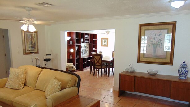 A living room with a sofa, a wooden coffee table, a dining area with chairs and a table, and a bookshelf. - Space for 6 3BR Close to Siesta Beach Downtown (Sarasota)