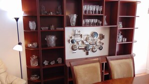 A dining area with a wooden table and chairs, surrounded by wooden shelves with glassware and decorative items. - Space for 6 3BR Close to Siesta Beach Downtown (Sarasota)