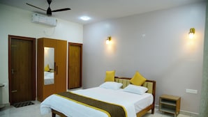 A bedroom with a bed, wardrobe, bedside table, and ceiling fan. - Aldur Residency (Chikkamagaluru)
