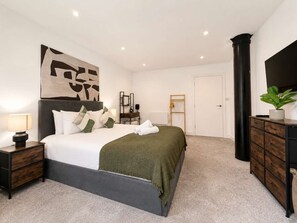 A modern bedroom with a large bed, bedside tables, a dresser, a mirror, a flat-screen TV, and a painting on the wall. - Modern 1BR - Sleeps 4 - Free Parking - Manchester (Manchester)