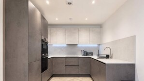 A modern kitchen with grey cabinetry, a herringbone-patterned floor, a built-in oven, and a sink with a modern faucet. - Modern 1BR - Sleeps 4 - Free Parking - Manchester (Manchester)