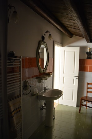 A bathroom with a sink, mirror, towel rack, and a door leading to another room. - Agriturismo Arona (SPERLINGA (EN))