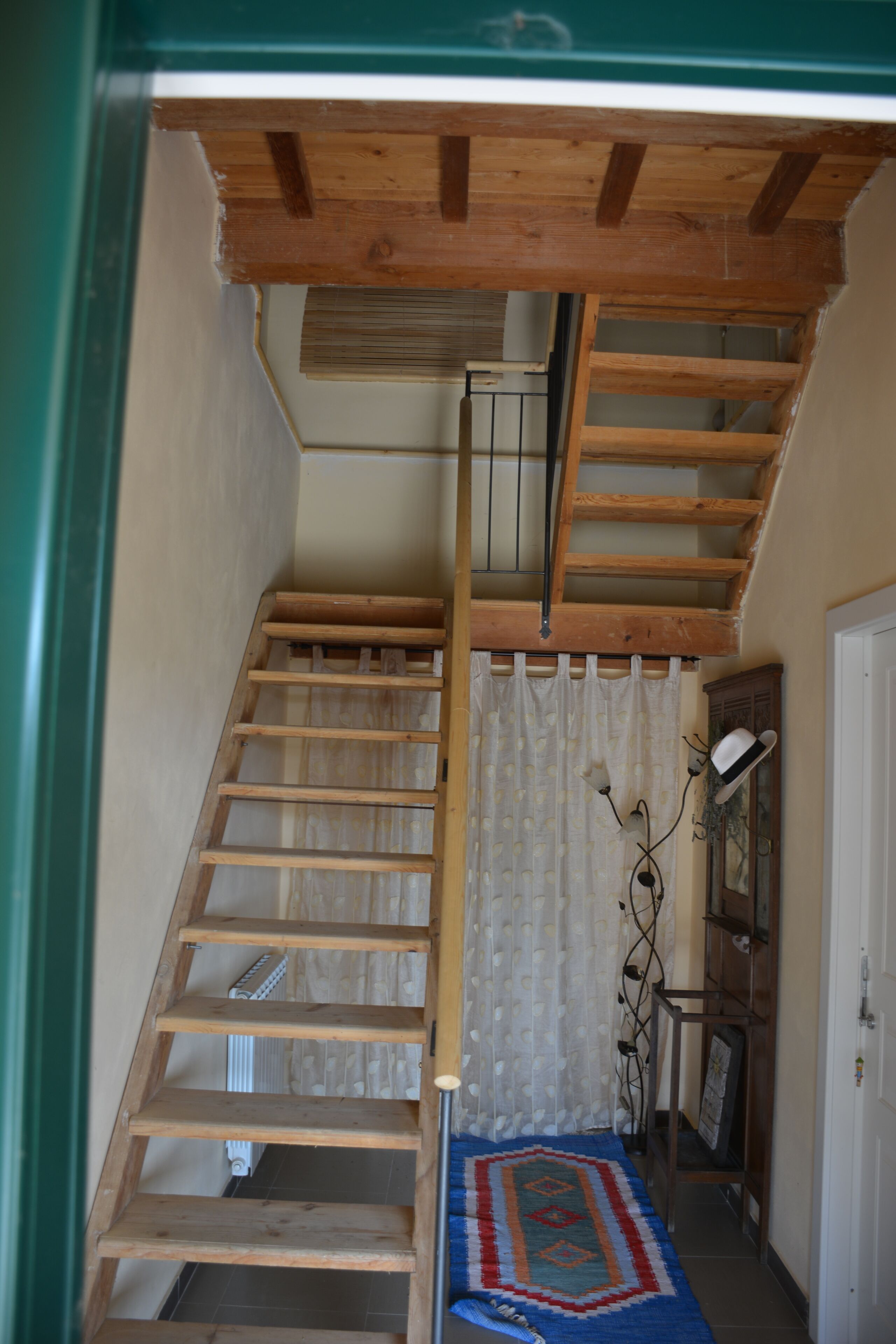A wooden staircase with a handrail, a patterned rug, and a radiator in the background.