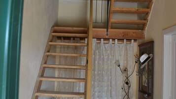 A wooden staircase with a handrail, a patterned rug, and a radiator in the background.