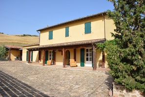 A two-story building with a tiled roof, multiple windows, and a stone-paved courtyard. - Agriturismo Arona (SPERLINGA (EN))