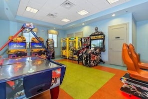 Een kamer met speelautomaten, een pooltafel en een deur.