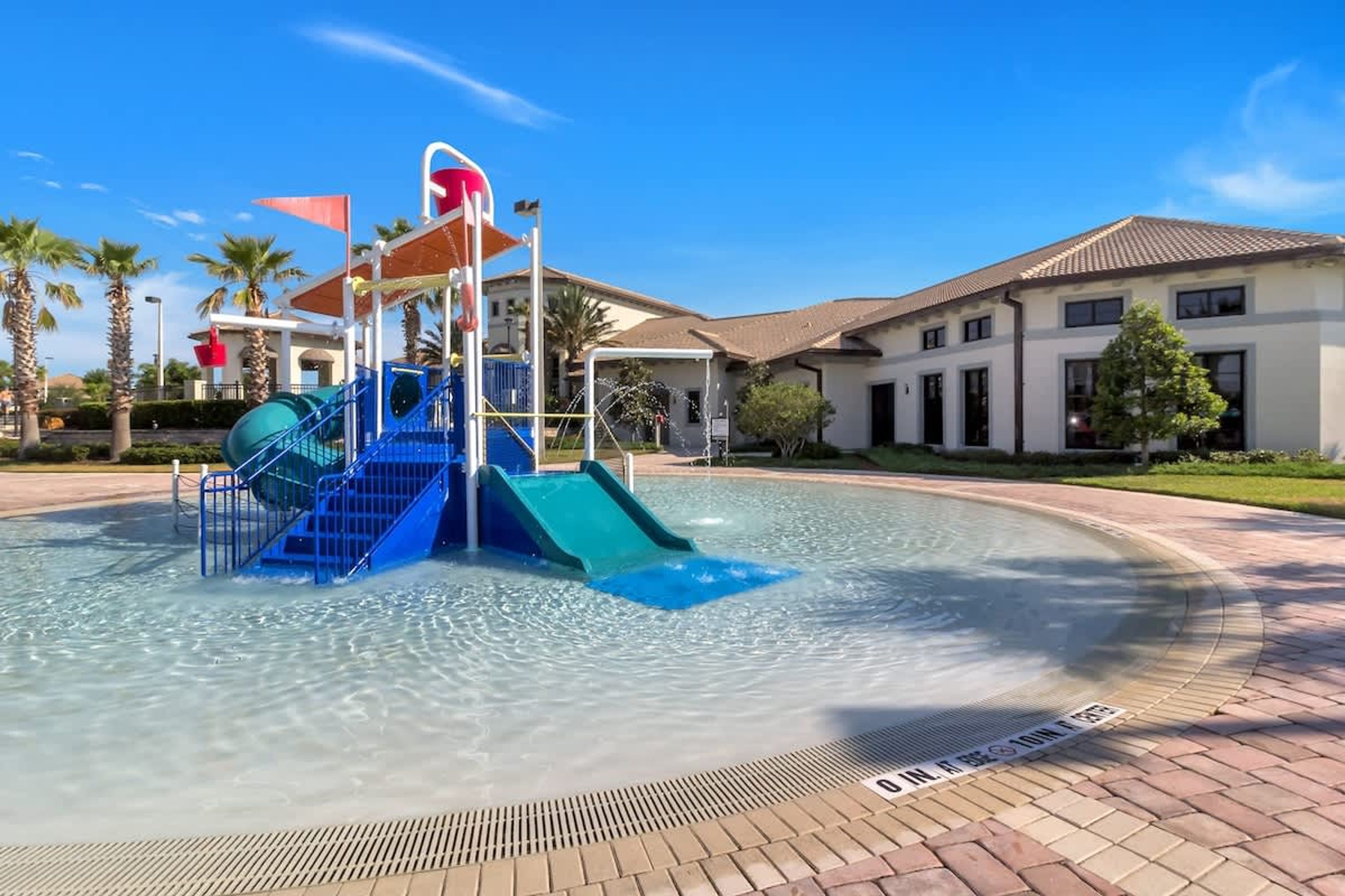 A water park with a blue slide and a water play structure.