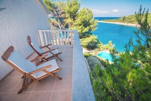 Un balcon avec deux fauteuils de jardin en bois et une piscine.