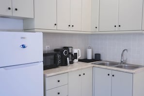 Eine Küche mit Kühlschrank, Mikrowelle, Kaffeemaschine und Spüle.