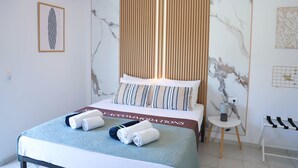 Habitación de hotel con cama, mesita de noche, aire acondicionado de pared y un cuadro en la pared.