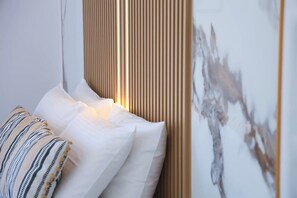 Ein Bett mit weißen Kissen und einem gestreiften Kissen, eine vertikale Holzverkleidung und eine Wand mit teilweise sichtbarer Malerei.