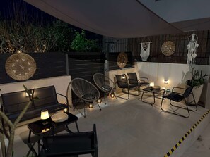 Eine Dachterrasse mit Sitzgelegenheiten, dekorativen Wandbildern und stimmungsvoller Beleuchtung.