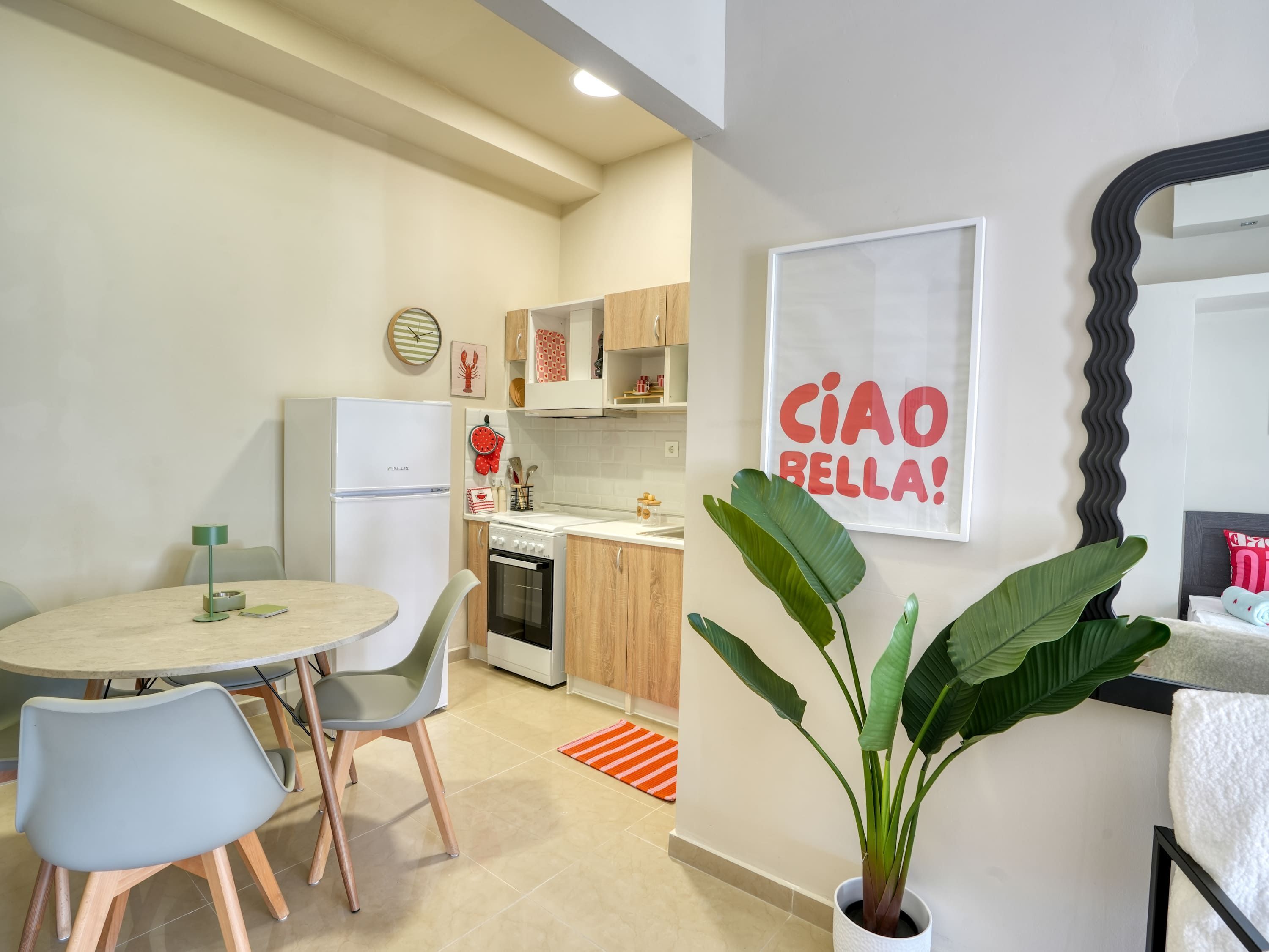 Cozinha moderna com geladeira, forno e área de refeições com mesa e cadeiras.