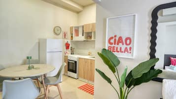 Cozinha moderna com geladeira, forno e área de refeições com mesa e cadeiras.