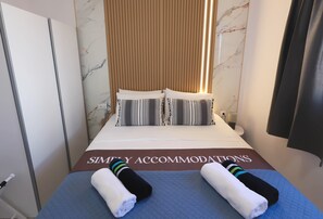 Une chambre d’hôtel avec un lit, des oreillers, une couverture soigneusement repliée et une serviette posée sur le lit.
