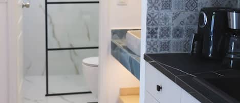 Un baño con inodoro blanco, ducha y suelo de baldosas.
