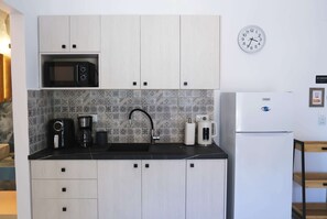 Eine Küche mit Mikrowelle, Kaffeemaschine, Spüle und Kühlschrank.