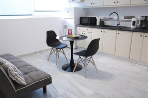 Eine moderne Küche mit Essbereich, inklusive einer Couch, zwei Stühlen, einem runden Tisch und einer Mikrowelle.