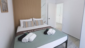 A hotel room with a bed, a green bedspread, a striped pillow, and a towel on the bed. - Apartment Simply 101 - Ammoudara Sandy Retreat (Malevizi)