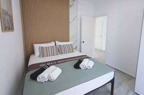 Ein Hotelzimmer mit Bett, einer grünen Tagesdecke, einem gestreiften Kopfkissen und einem Handtuch auf dem Bett.