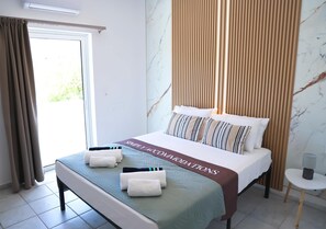 Ein Hotelzimmer mit einem Bett, einer Bank, einem kleinen Tisch und Blick auf Grün.