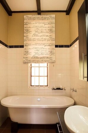 A bathroom with a bathtub, a sink, and a large piece of paper with text on the wall. - Remhoogte Mountain Lodge (Skeerpoort)