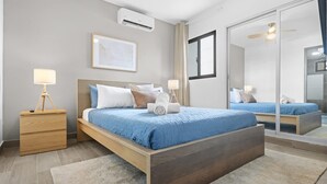 A modern bedroom with a large bed, bedside tables, a mirror, and an air conditioning unit. - NOK Cozy 1BR Retreat With Pool Near Punta Cana Beaches (Punta Cana)