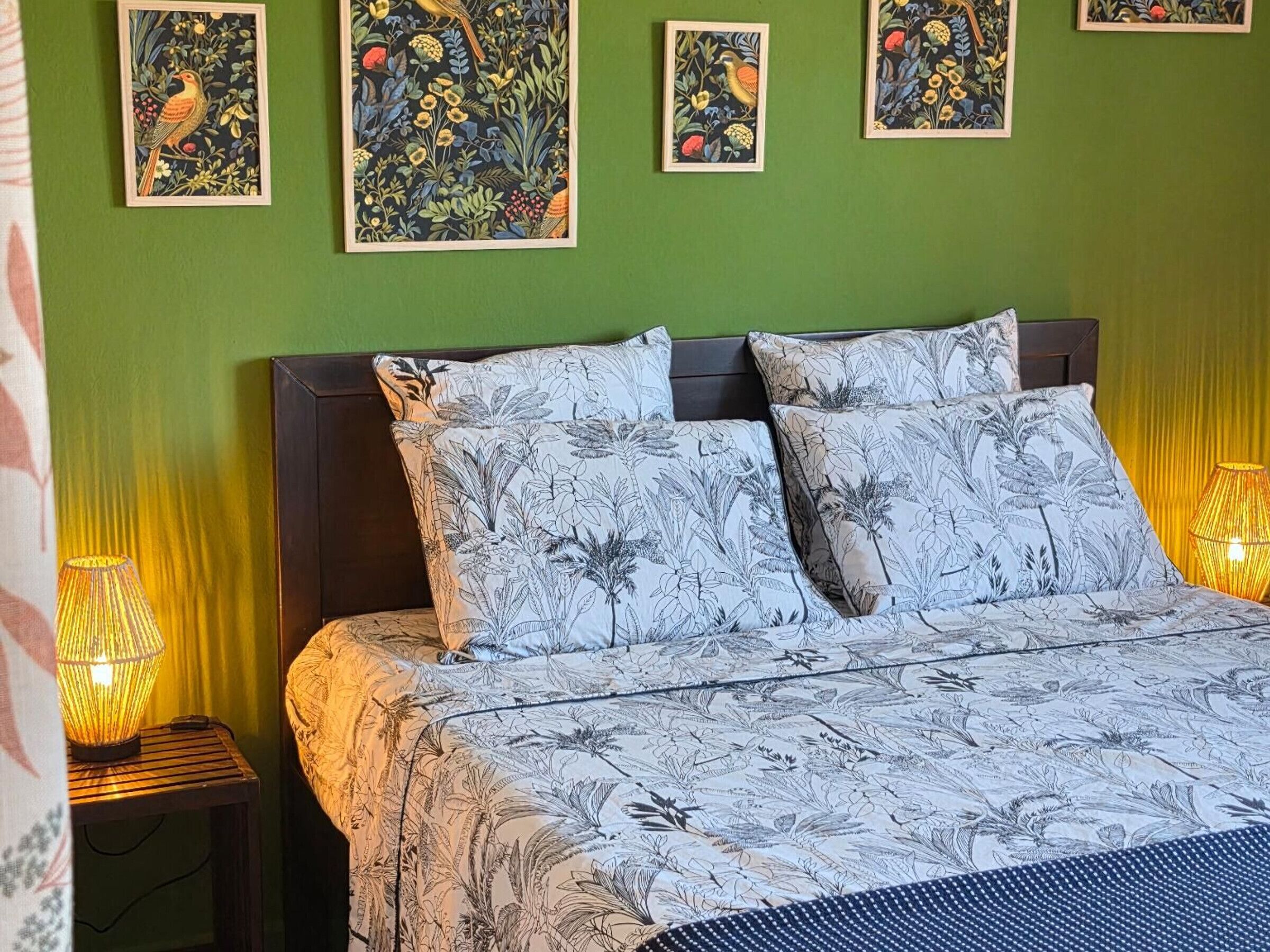 A bed with floral-patterned bedding, a dark headboard, and two bedside lamps.