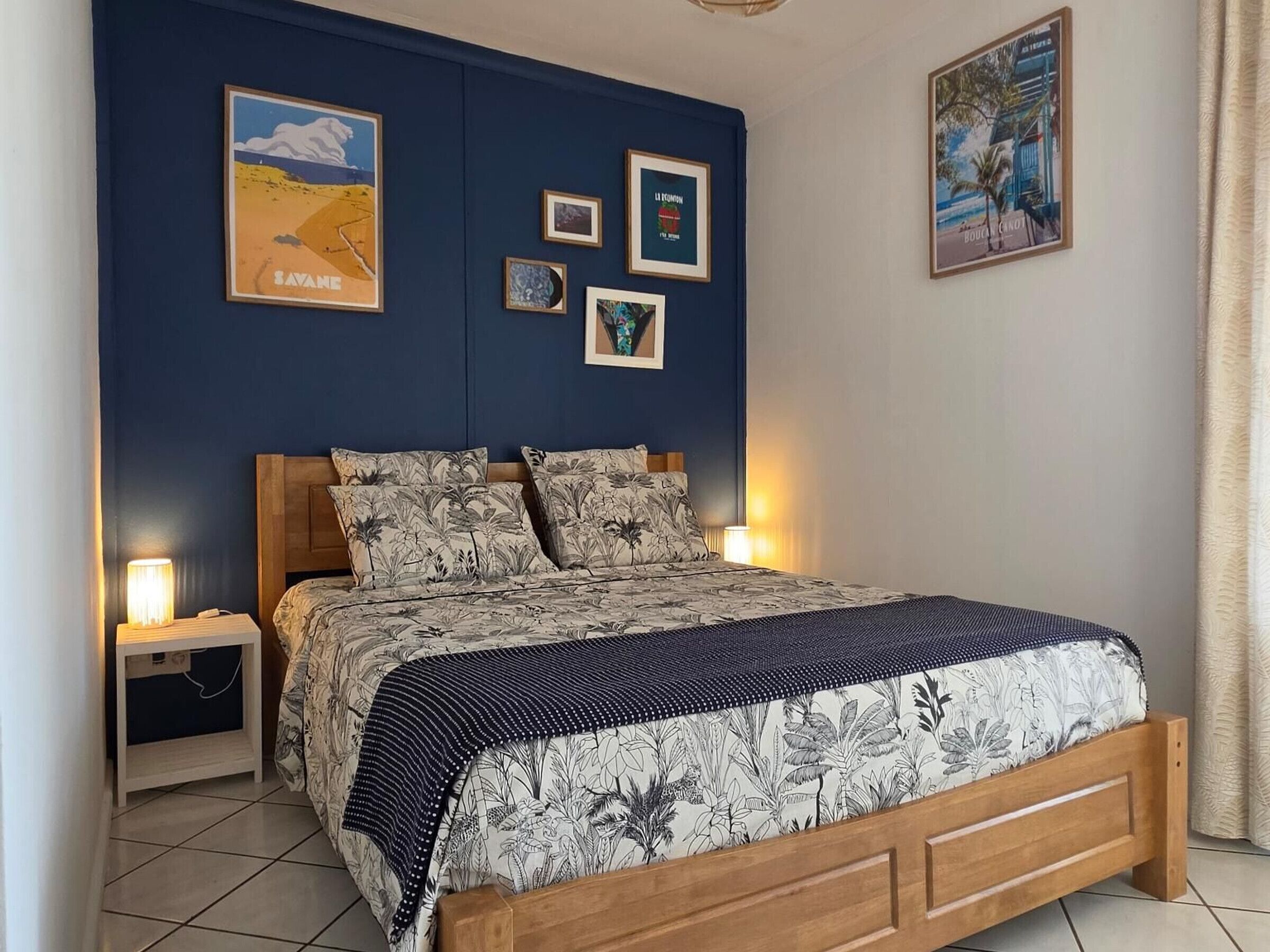 A bedroom with a bed, nightstands, and wall art.
