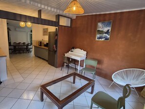 Un comedor con una mesa y sillas, una cocina al fondo y un cuadro en la pared.