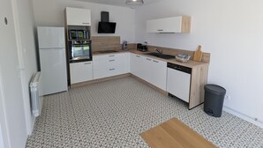 Eine kleine Küche mit weißen Schränken, einem Einbauofen, einer Spüle und einer Holz Arbeitsplatte.