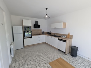 A compact kitchen with white cabinets, a built-in oven, a sink, and a wooden countertop. - Peaceful cottage between fields and forests - 6 guests (Gidy)