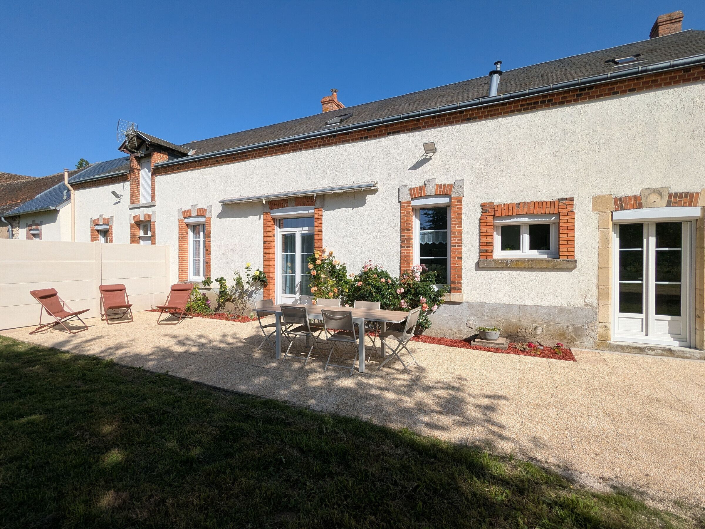 A house with a patio, outdoor seating, and a garden.