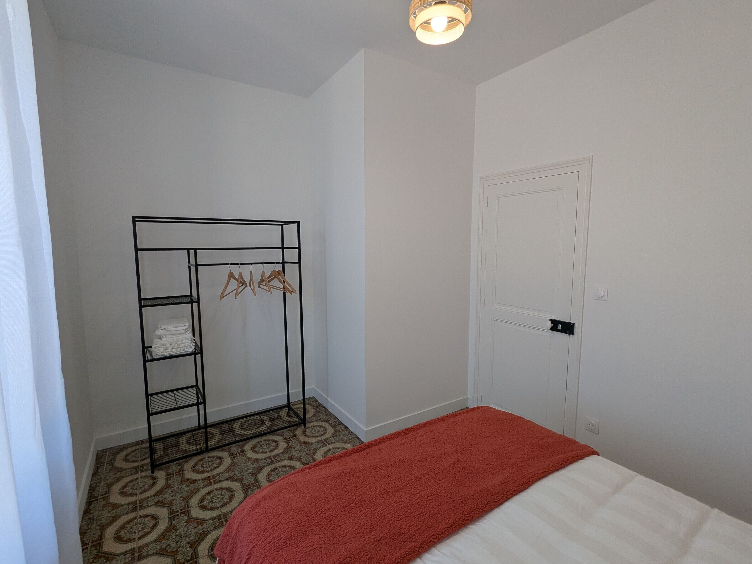 Un dormitorio con cama, armario y suelo estampado.