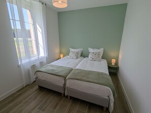Een kamer met twee bedden, een raam en een groene wand.
