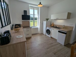 Une cuisine moderne Ă©quipĂ©e dâun lave-linge, dâun lave-vaisselle et dâune fenĂȘtre donnant sur un espace verdoyant.