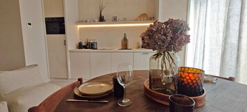 A dining table with a glass vase, wine glass, and candle holder.
