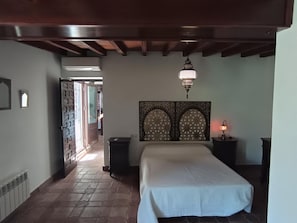 Une chambre à coucher comprenant un lit, une tête de lit décorative, un luminaire suspendu et une table de chevet avec une lampe.