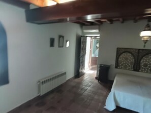 Une pièce comprenant un lit, un radiateur, une porte et un mur orné d’un panneau décoratif.