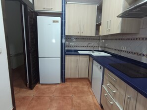 A compact kitchen with a refrigerator, sink, cabinets, and a tiled backsplash. - Charming house with pool - 6 guests (Granada)