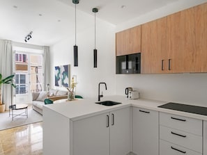 A modern kitchen with white cabinetry, a black countertop, and a built-in microwave. - Apartment in the heart of Málaga (Málaga)
