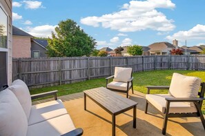 An outdoor patio area with a sofa, two chairs, and a table. - Spacious East Montgomery Home With Patio (Montgomery)