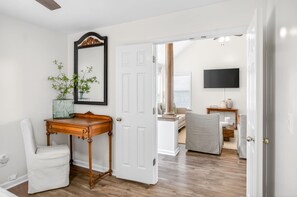 A hallway with a white door, a mirror, a small table with a vase, and a chair. - Spacious East Montgomery Home With Patio (Montgomery)